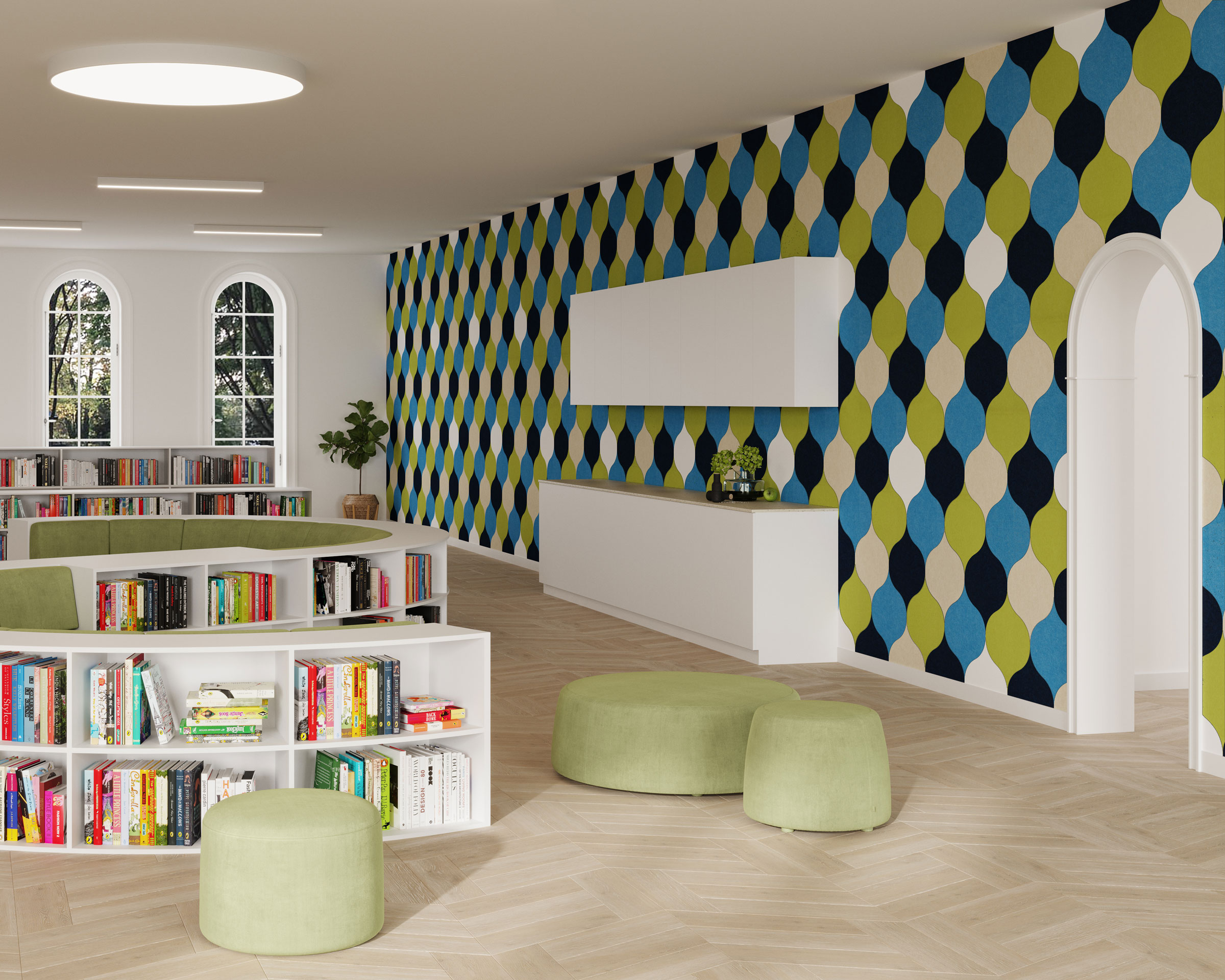 A modern reading area features low white bookshelves stocked with colorful books. Green cushioned seats are scattered around the wooden floor. The far wall is adorned with vibrant acoustic felt wall tiles in blue and green hues, and windows let in natural light.