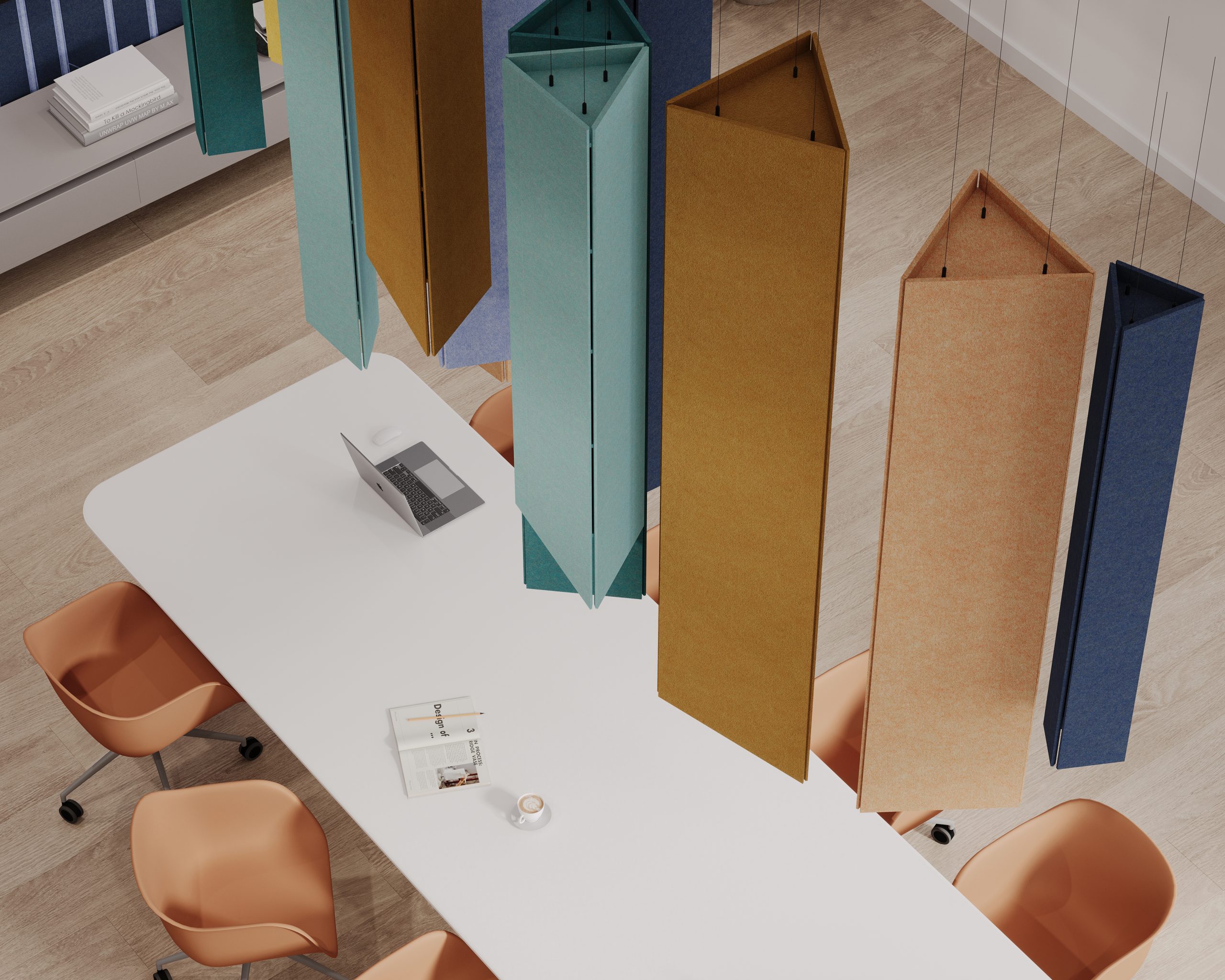 A top-down view of a modern office meeting area with a white table, equipped with a computer and documents, surrounded by stylish orange chairs and colorful sound-absorbing panels hanging from the ceiling.