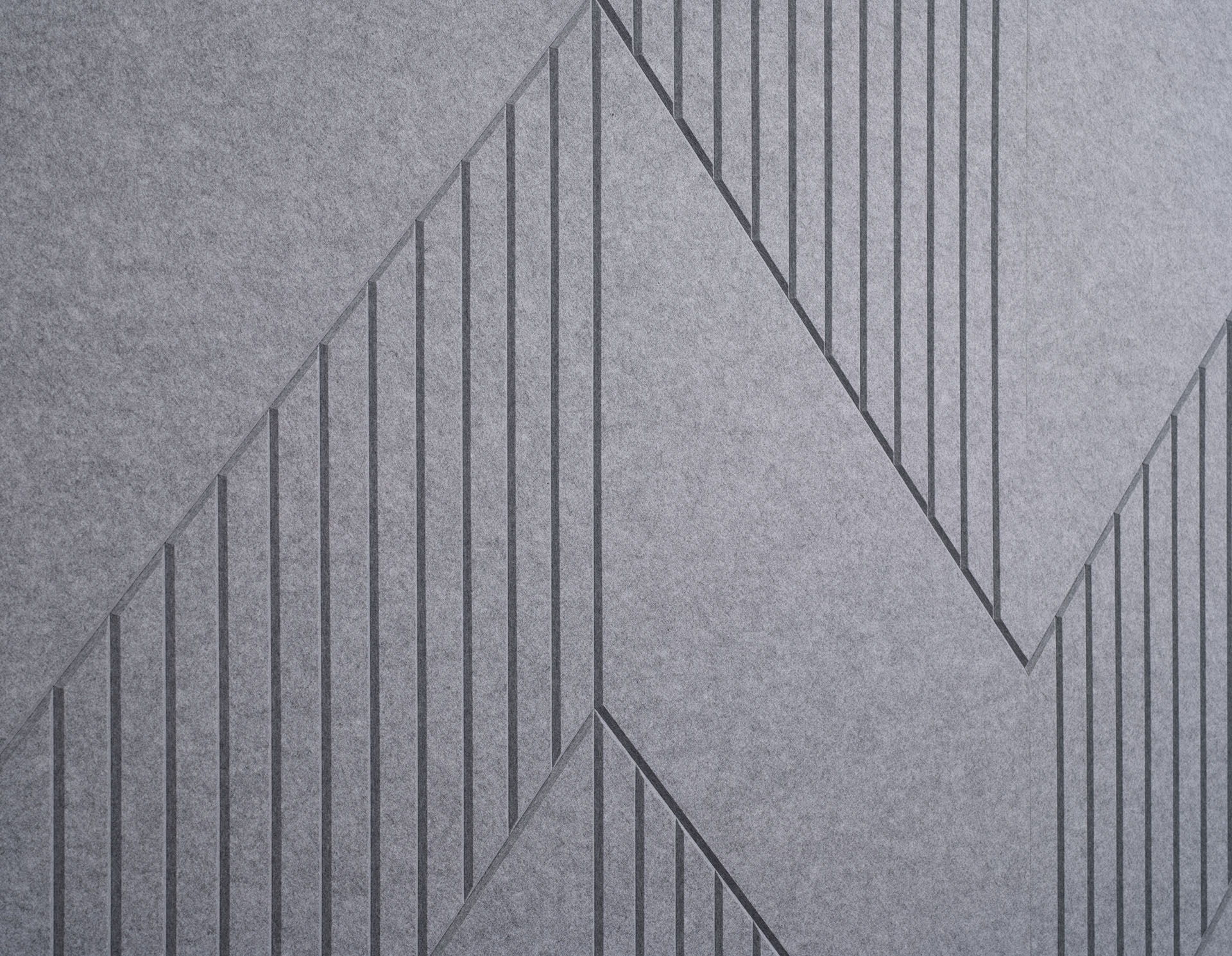 Premier acoustic felt gray wall panel with a modern, geometric design featuring a zigzag pattern. The panel incorporates vertical lines and varying shades of gray to create a visually striking and textured surface.