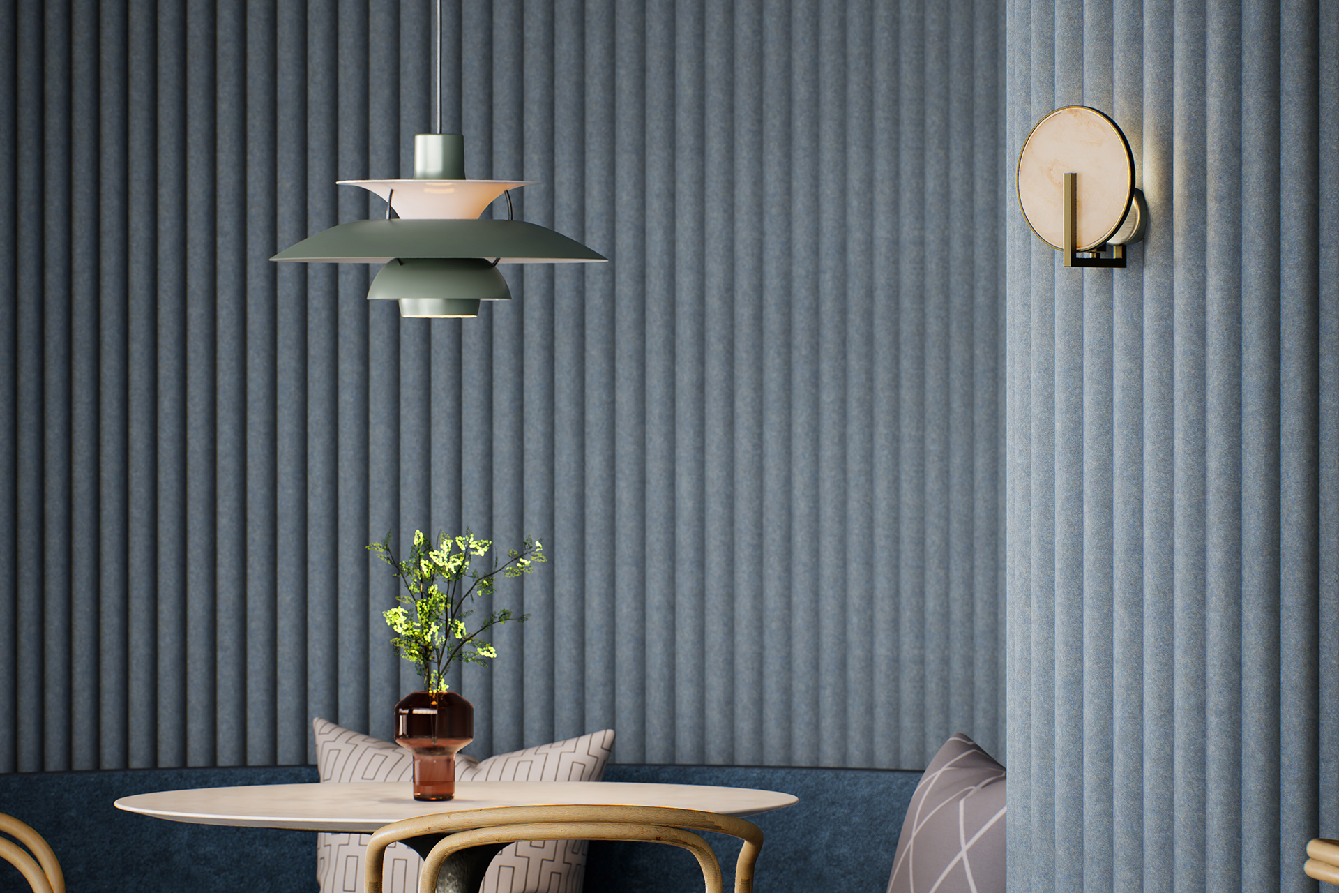 A modern interior with a round table and wooden chairs. A brown vase with green flowers sits on the table. A green pendant lamp hangs above, and a circular wall light is attached to ribbed blue walls.