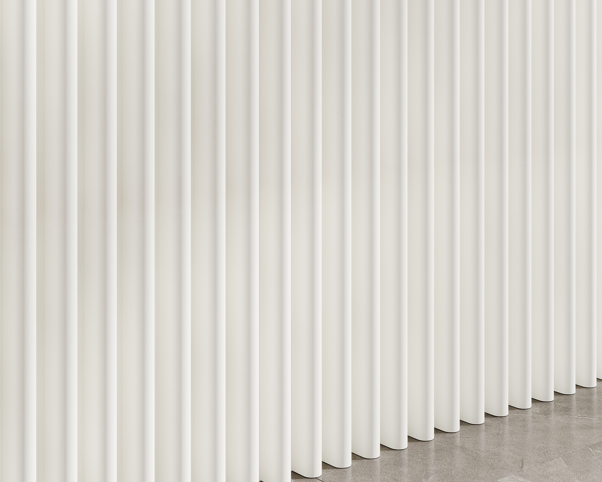 Close-up of a series of tall, vertical white panels made from acoustic felt, creating a modern and minimalist pattern. The panels are evenly spaced and extend for the full height of the image, casting subtle shadows on the floor below.