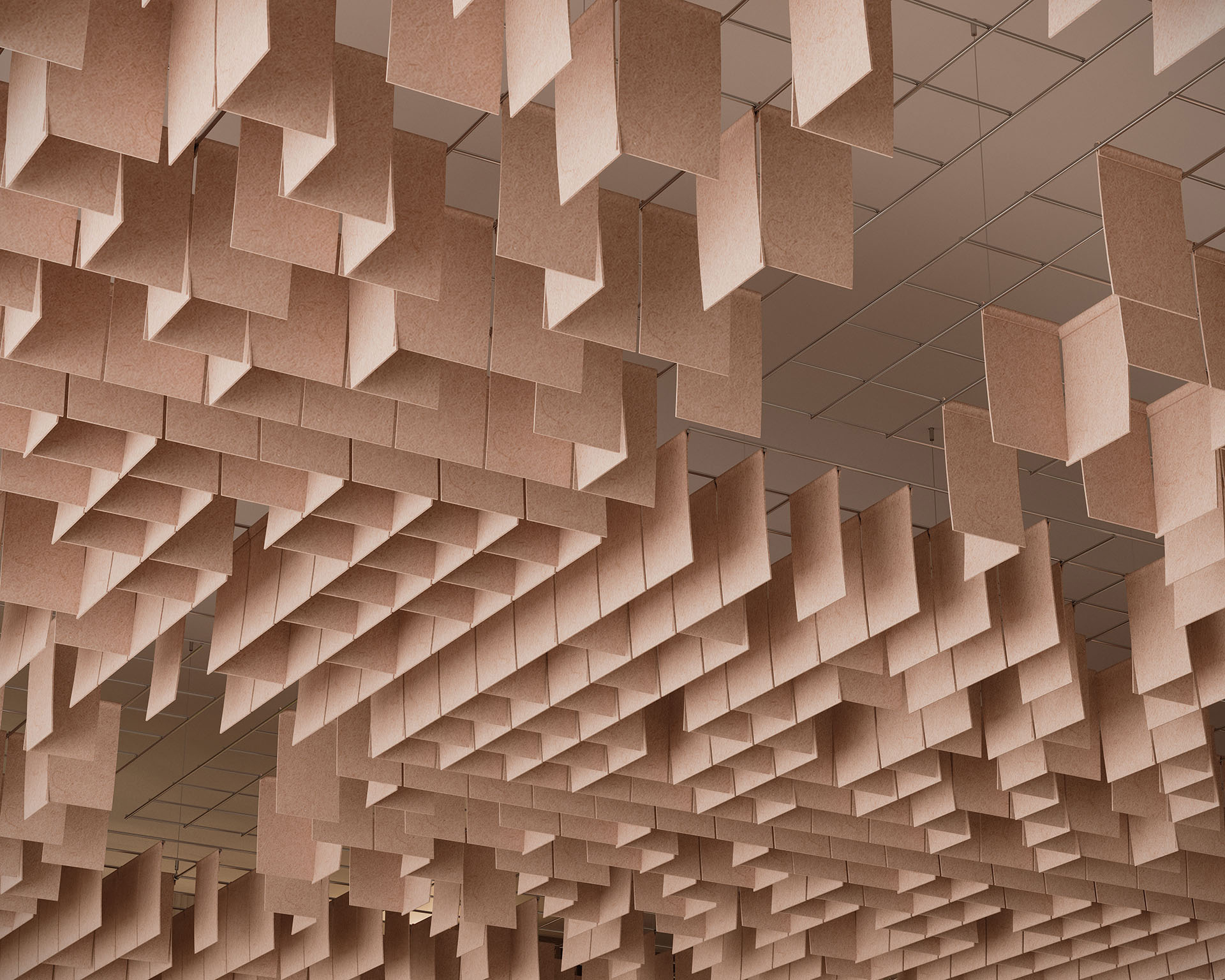 The ceiling features numerous hanging rectangular panels of acoustic felt, arranged in an artistic pattern like floating clouds. These light brown elements create an abstract geometric design, enhancing the architectural interest of the space with their natural charm.