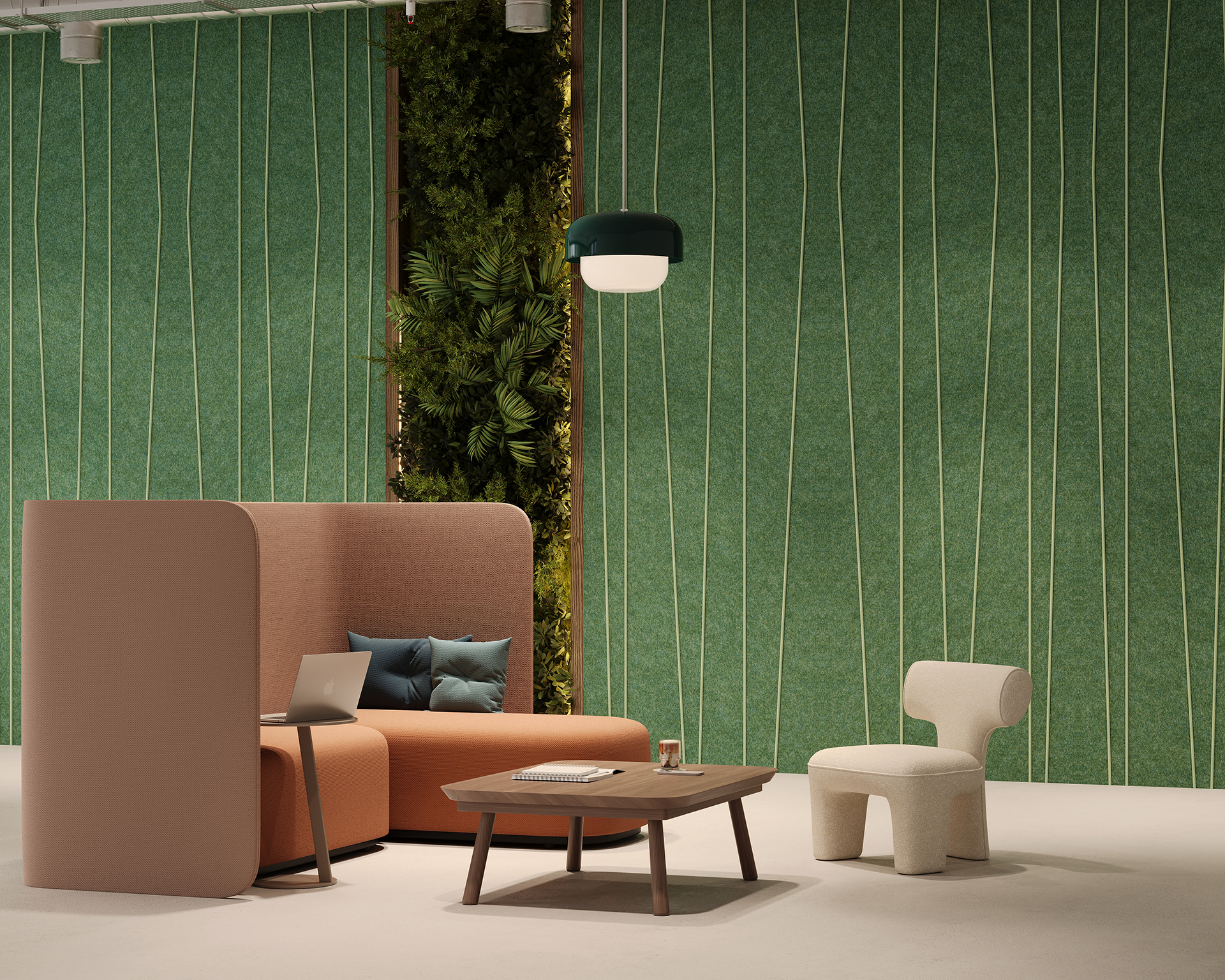 A modern lounge area with a curved sofa and several cushions, a small wooden coffee table, and a white chair. A laptop is on the sofa. The background features a green acoustic felt wall with plant accents and a hanging light fixture.