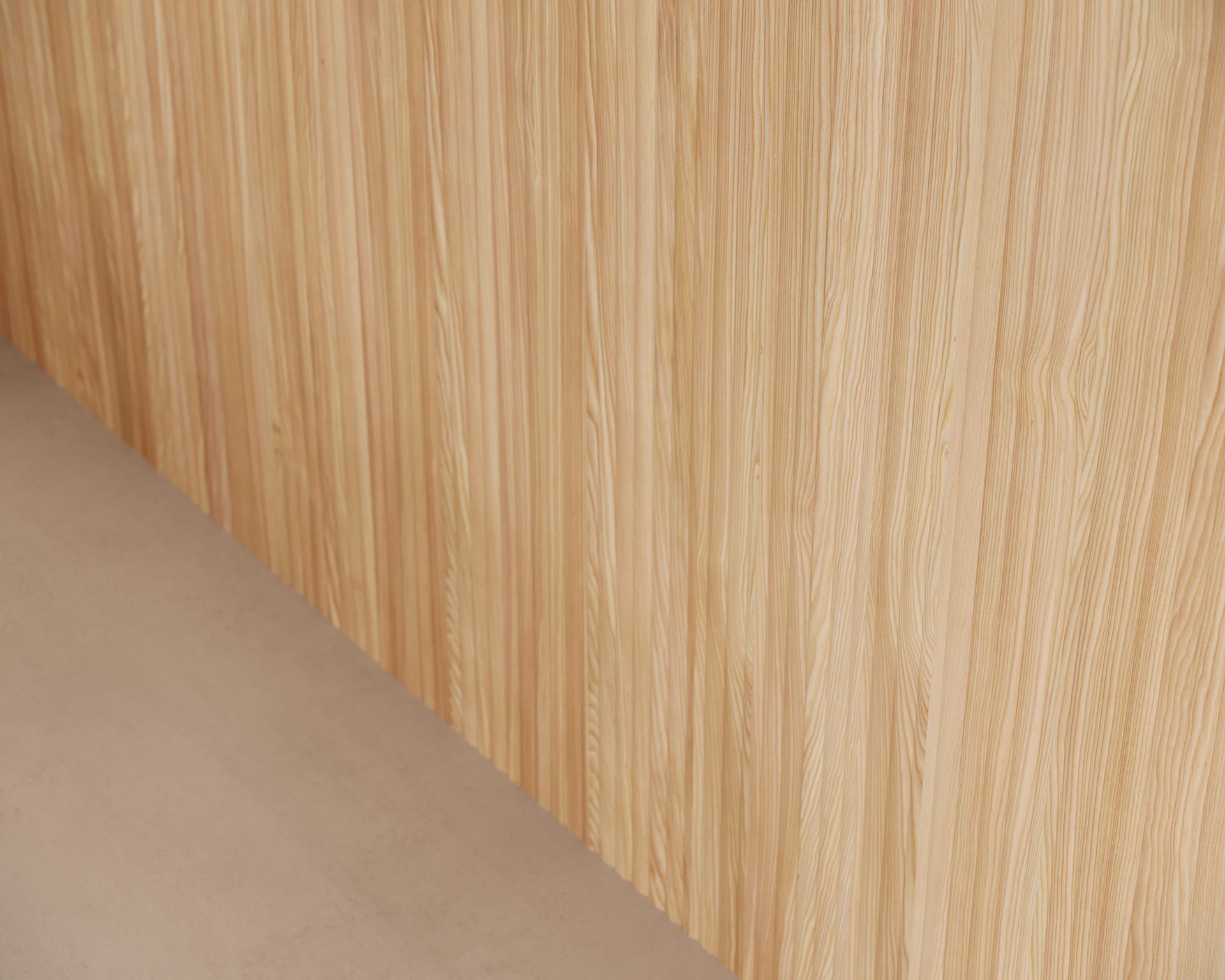 Light brown woodgrain acoustic felt wall with vertical grain pattern next to a neutral-colored floor.